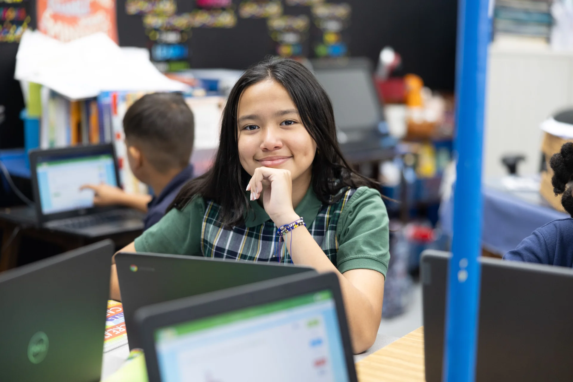 student smiling while sitting at laptop