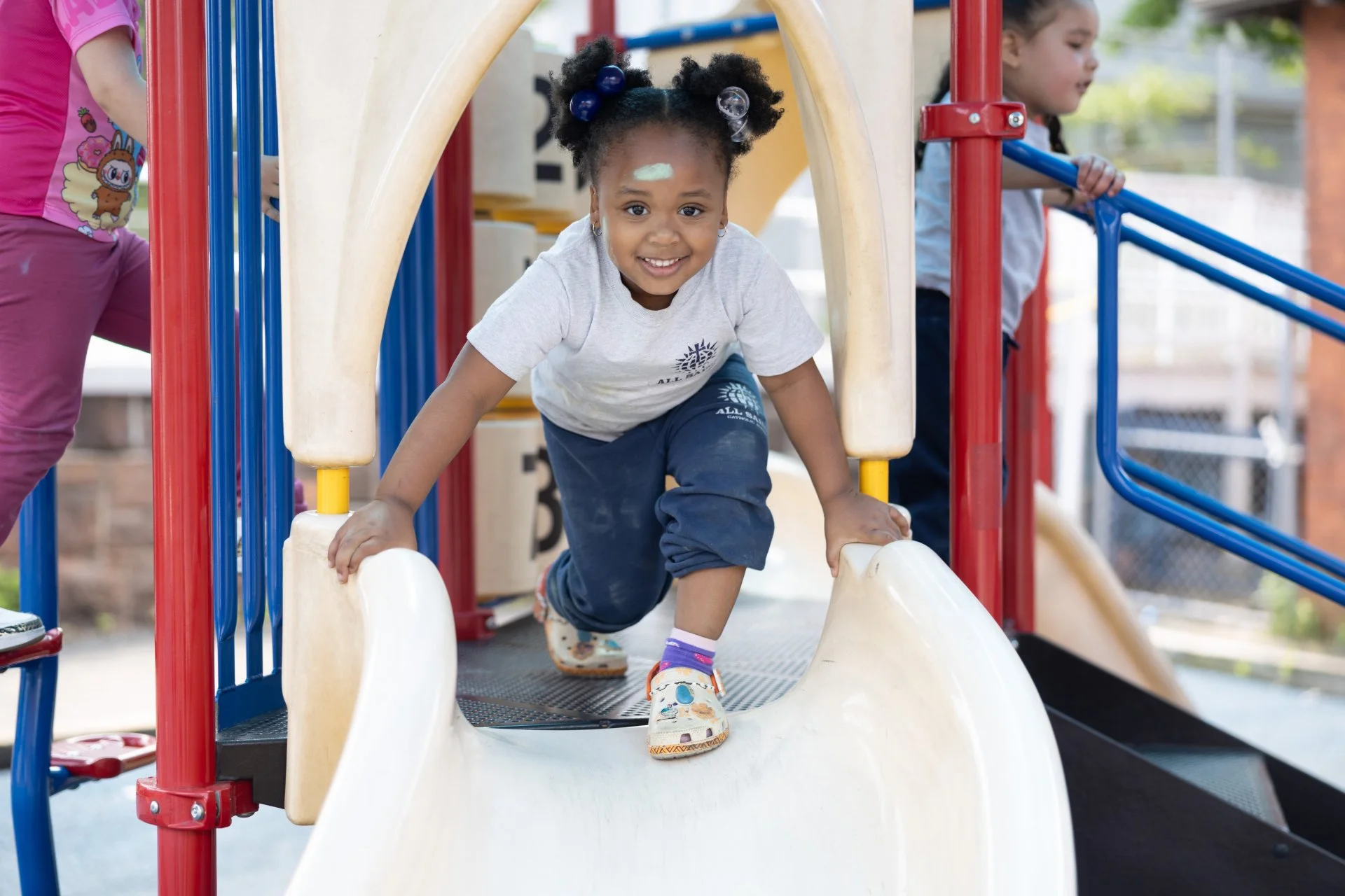 student smiling while playing on slide