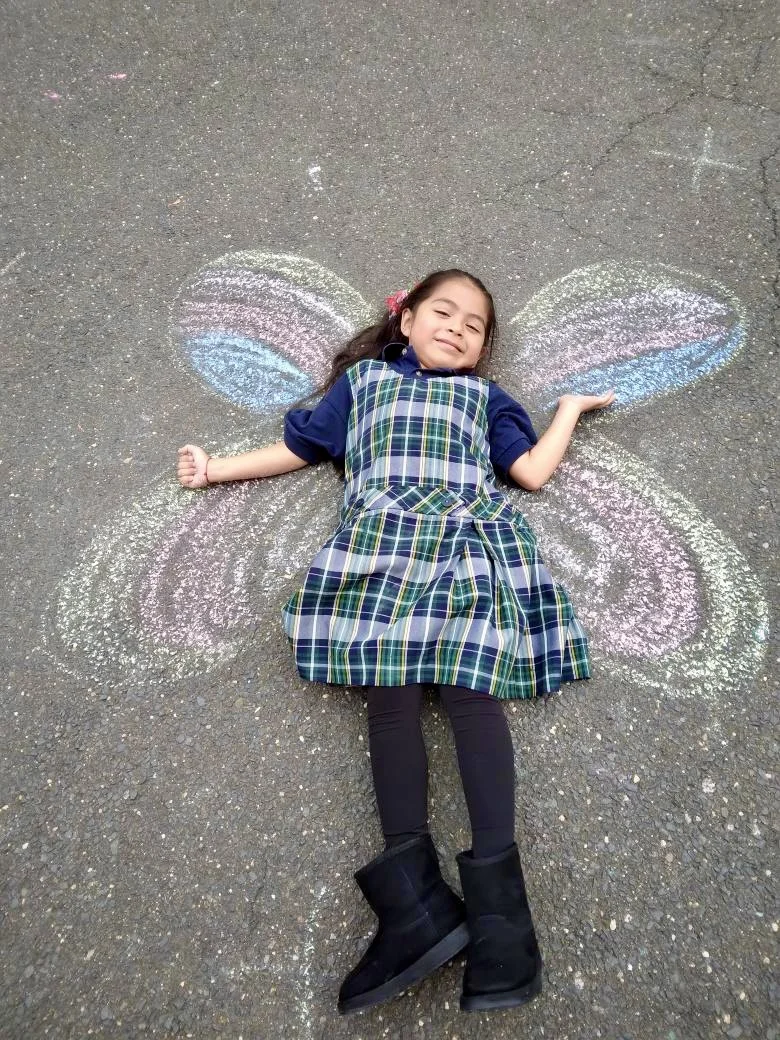 student laying down on chalk butterfly